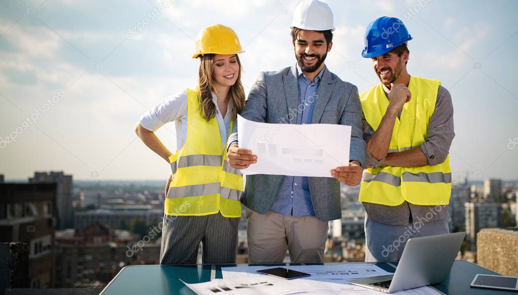 Team of architects and engineer in group on construciton site check documents