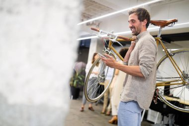 Modern ofiste bisiklet taşıyan mutlu iş arkadaşı