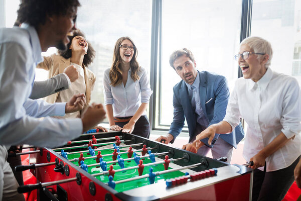 Employees playing table soccer indoor game in the office during break time to relieve stress from work