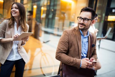 Mutlu iş adamları dışarıda yürürken tartışıyor ve gülümsüyor.