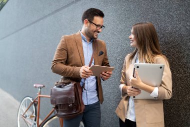 Mutlu iş adamları dışarıda yürürken tartışıyor ve gülümsüyor.
