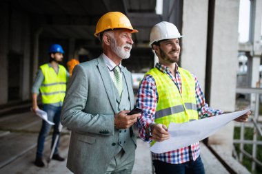 İnşaat şantiyesinde çalışan inşaat mühendisi grubu ve inşaat sahasında yönetim