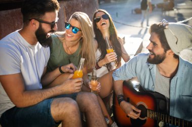 Bir grup arkadaş dışarıda gitar çalarak yaz gününün tadını çıkarıyorlar. Mutlu gençler birlikte iyi vakit geçiriyorlar.