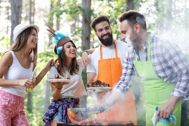 Açık havada barbekü akşam yemeği bira içme ve yemek yeme mutlu arkadaş grubu
