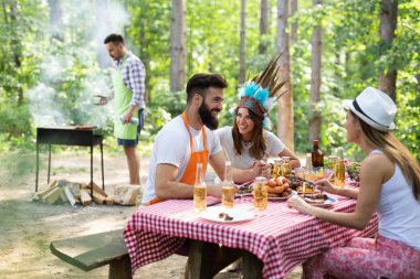 Açık havada barbekü akşam yemeği bira içme ve yemek yeme mutlu arkadaş grubu