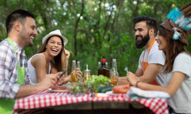 Açık havada barbekü akşam yemeği bira içme ve yemek yeme mutlu arkadaş grubu