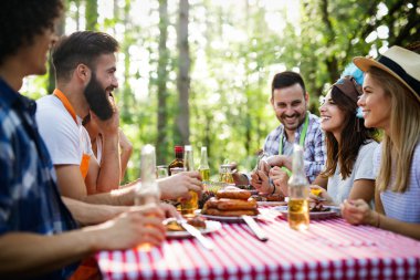 Açık havada barbekü akşam yemeği bira içme ve yemek yeme mutlu arkadaş grubu