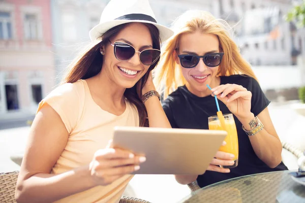 İki mutlu genç kadın dijital tablet kafede açık kullanma