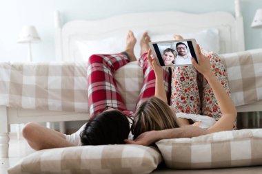 Birlikte kullanarak dijital tablet yatak odasında genç çekici çift