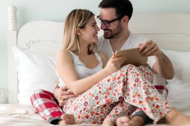 Birlikte kullanarak dijital tablet yatak odasında genç çekici çift