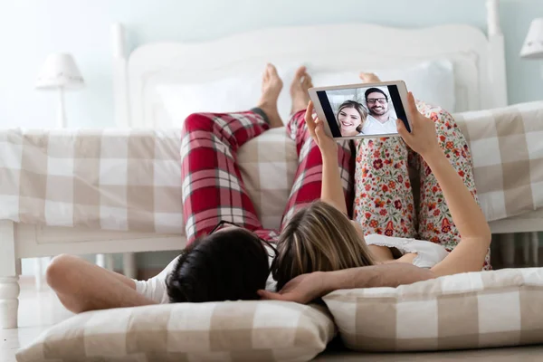 Birlikte kullanarak dijital tablet yatak odasında genç çekici çift