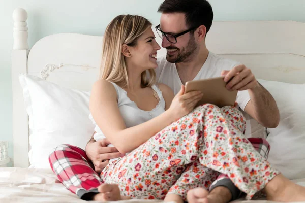 Birlikte kullanarak dijital tablet yatak odasında genç çekici çift