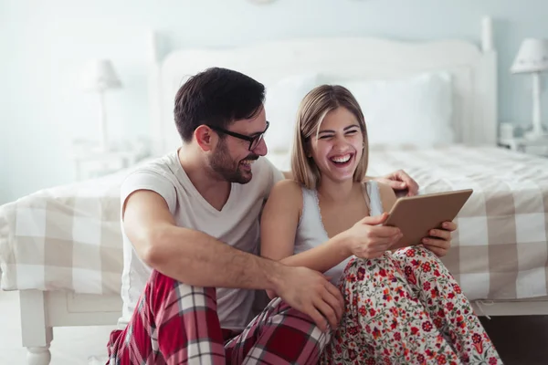 Birlikte kullanarak dijital tablet yatak odasında genç çekici çift