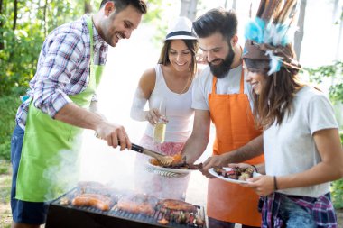 Açık havada barbekü akşam yemeği bira içme ve yemek yeme mutlu arkadaş grubu