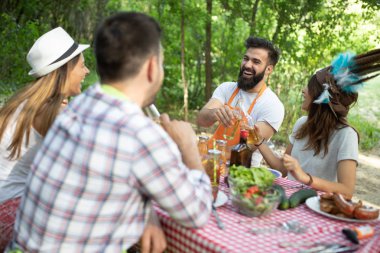 Açık havada barbekü akşam yemeği bira içme ve yemek yeme mutlu arkadaş grubu
