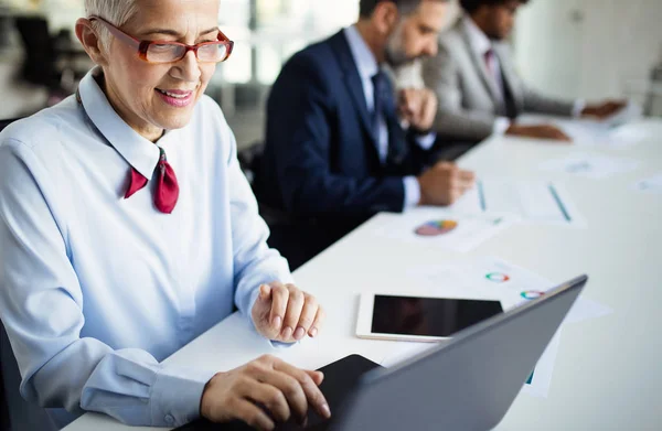 Portrait of happy business people discussing working together in office