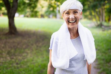Parkta gülümseyen sportif yaşlı kadın portresi