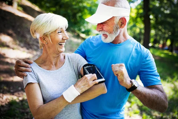 Beautiful senior couple running outside in sunny forest