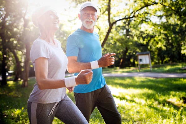 Beautiful senior couple running outside in sunny forest