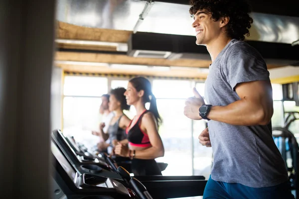 Group of young fit people running on treadmill in gym