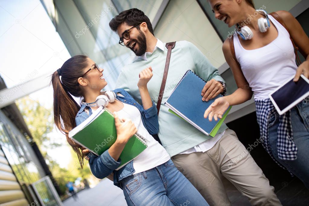 Happy young university students studying with books at university. Group of people in college