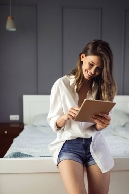 Güzellik ağda sörf yapıyor. Dijital tablet kullanan çekici genç kadın