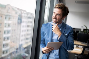 Ofiste dijital tablet kullanarak emin genç işadamı portresi