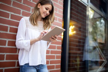 Şehirde tablet kullanarak güzel genç mutlu kadın