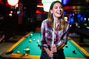 Oyun ve eğlenceli kavram. Bilardo ile eğlenen genç mutlu kız