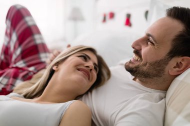 Genç çekici mutlu çift yatakta romantik vakit geçiriyor