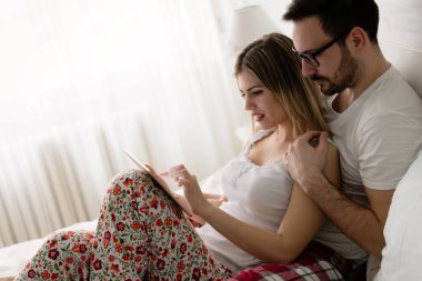 Genç çekici çift yatak odasında dijital tablet kullanma