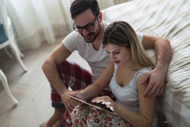 Genç çekici çift yatak odasında dijital tablet kullanma