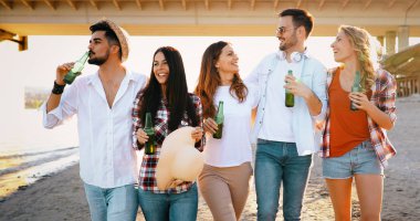 Arkadaş grubu plaj partisi. Neşeli genç insanlar güzel birlikte sahilde vakit ve bira içmek