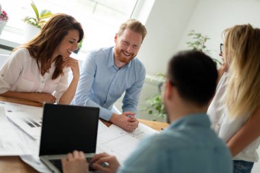 İş arkadaşlarıyla birlikte ofis masasında otururken çalışan ve iletişim kuran bir grup genç iş adamı