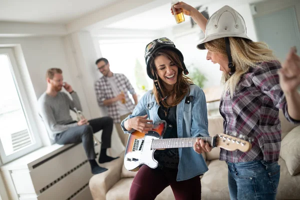 Friends at home enjoying singing and playing guitar, having fun