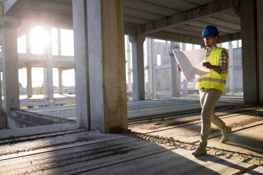 İnşaatta çalışan ve blueprint tutan yakışıklı mühendisi