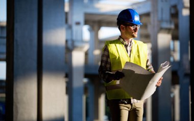 Genç iş adamı inşaat sitesi mühendis mavi baskı ile