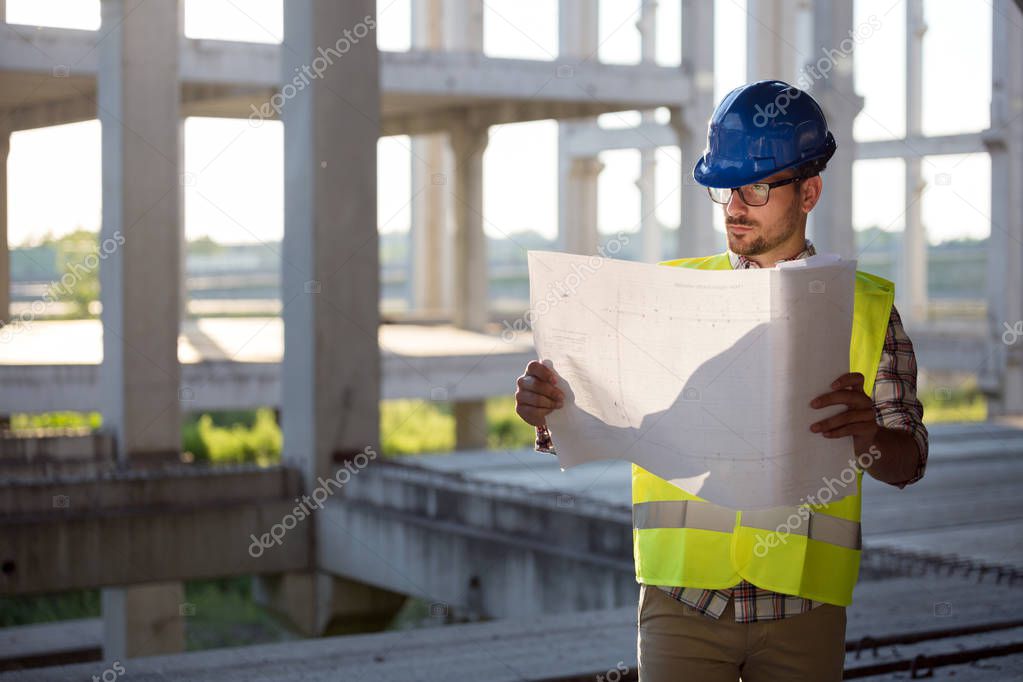 Young business man construction site engineer with blue print