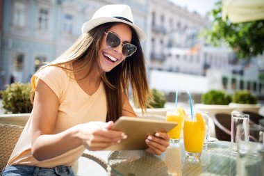 Bir yaz kafede masada otururken bir tablet tutan gülümseyen kız