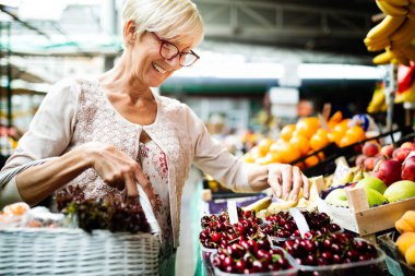 Picture of senior happy woman at marketplace buying vegetables and fruits clipart