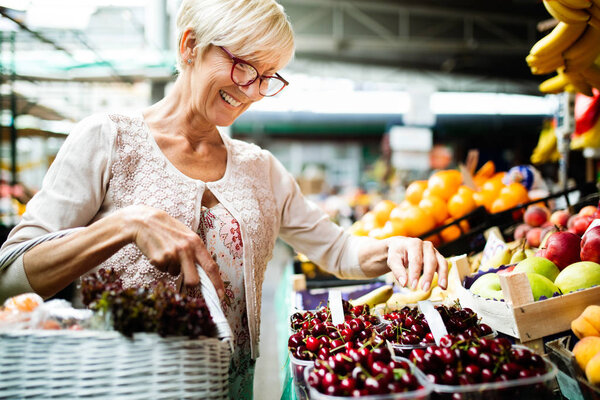 Picture of senior happy woman at marketplace buying vegetables and fruits