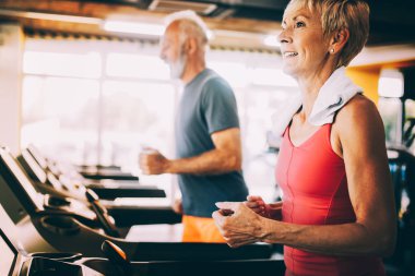 Spor salonunda koşu bandında koşan son sınıf öğrencileri.