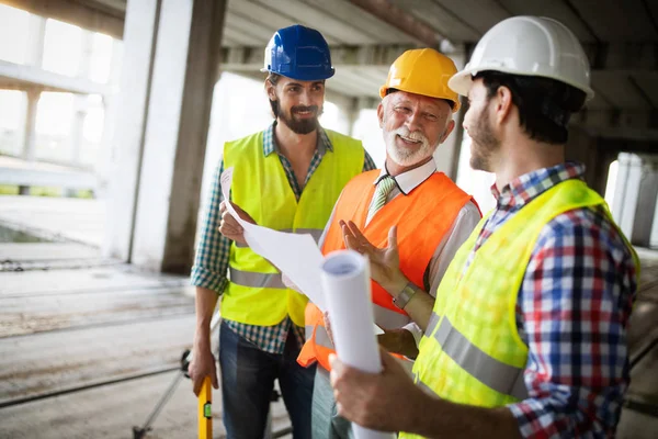 Team aus Architekten und Ingenieuren in einer Gruppe auf der Baustelle überprüfen Dokumente und Geschäftsabläufe — Stockfoto