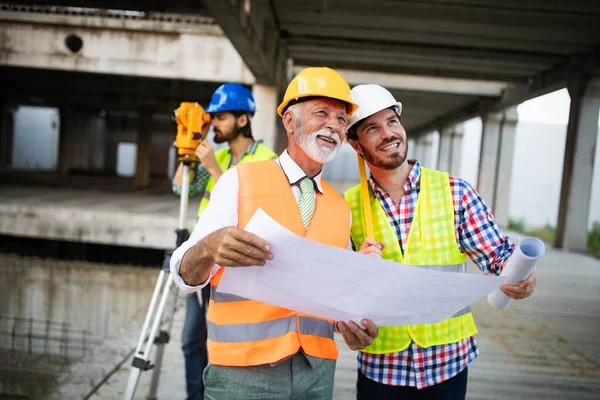 Team aus Architekten und Ingenieuren in einer Gruppe auf der Baustelle überprüfen Dokumente und Geschäftsabläufe — Stockfoto