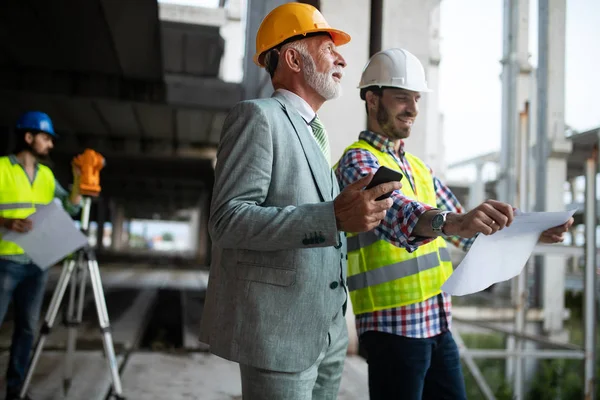 Zespół architektów i inżynierów w grupie zajmujący się dokumentami kontrolnymi budowy i przepływem pracy — Zdjęcie stockowe