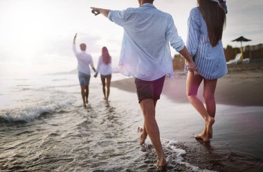 Gün batımı güneş ışığı altında sahilde eğlenen arkadaşlar.