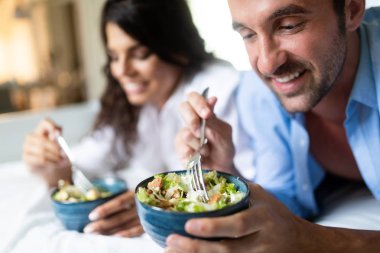 Mutlu genç çift sabah yatakta kahvaltı. Güzel çift bir yatakta yatarken