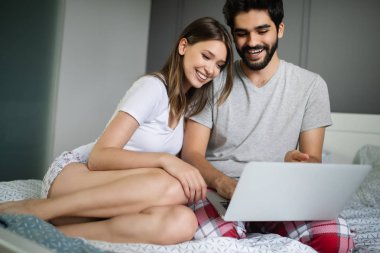 Genç çift dizüstü bilgisayar ile evde rahatlatıcı. Aşk, mutluluk, insanlar ve eğlenceli kavram.