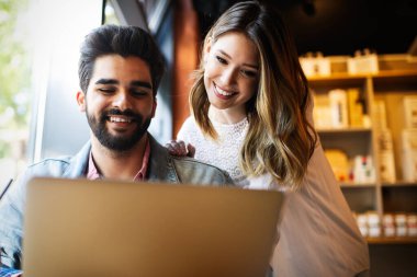 Üniversitede kafede dizüstü bilgisayar kullanarak gülümseyen arkadaşlar