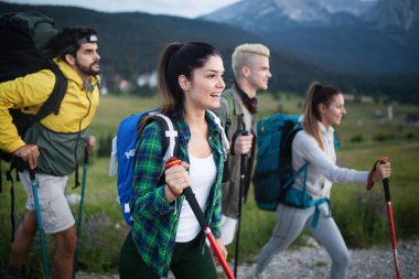 Sırt çantaları ve tırmanma sopasıyla tepeye tırmanan arkadaşlar.